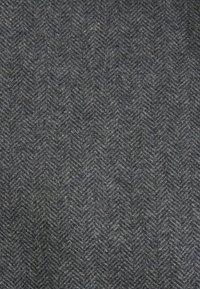 Tissu en laine chevron gris foncé avec un motif zigzag diagonal texturé.