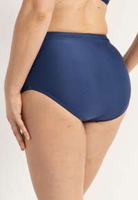 Ylhäältä vyötäröstä korkealle ulottuva uimahousujen alaosa tummansinisenä. Suorassa, joustavassa kankaassa on kohtalainen peittävyys. Ei näkyviä kuvioita tai koristeita.