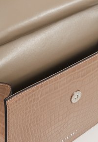 Borsa in pelle color cacao con motivo a coccodrillo, chiusura metallica a scatto, rivestimento interno beige liscio e cuciture a vista lungo i bordi.