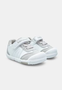 White and gray sneakers with a padded tongue, mesh and suede panels, adjustable hook-and-loop strap, and textured rubber sole.