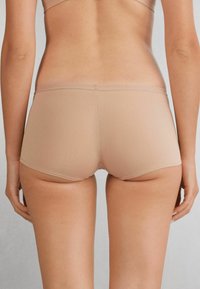 Boxers cortos beige sin costuras, hechos de una tela suave, con una cintura baja y sin costuras visibles para un aspecto suave.
