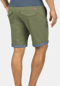Olivgröna shorts i bomull med en uppvikt fåll och denimdetaljer, två bakfickor med knappar och en liten logotagg på midjebandet.