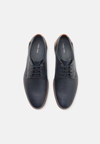 Pantofi bleumarin din piele texturată, cu un design cu șireturi, vârf rotund și accente din piele maro la toc și în jurul tălpii.