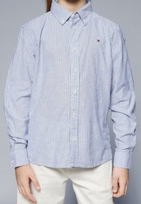 Camicia a righe button-up in azzurro chiaro e bianco, realizzata in cotone, con colletto classico, maniche lunghe e un piccolo logo sul petto.