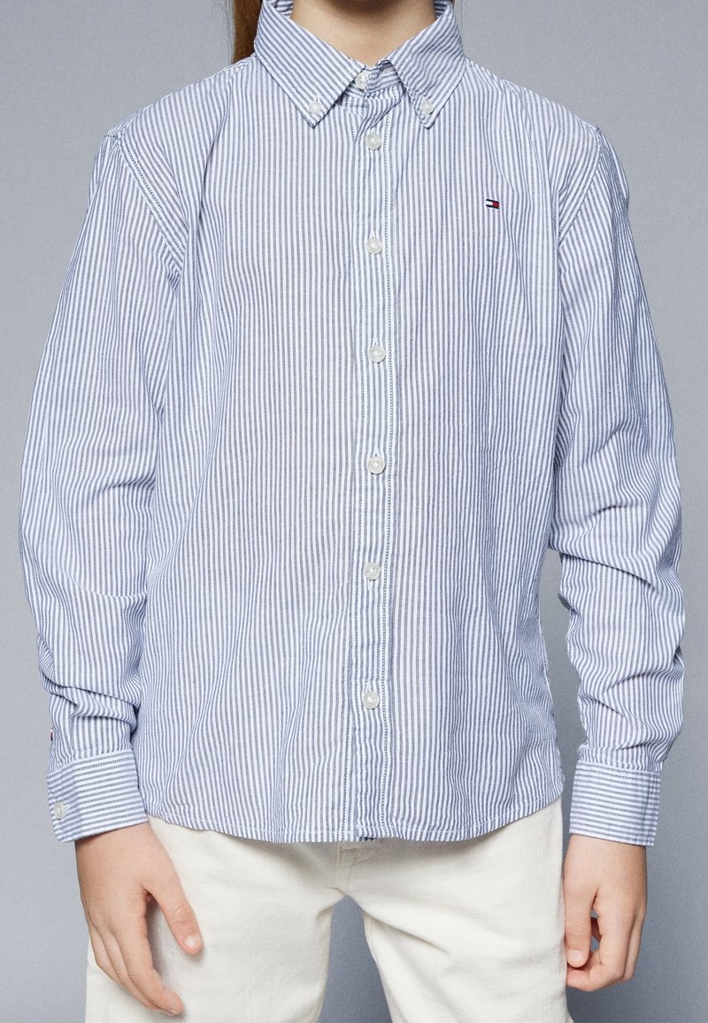 Camicia a righe button-up in azzurro chiaro e bianco, realizzata in cotone, con colletto classico, maniche lunghe e un piccolo logo sul petto.