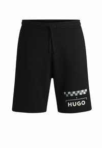 Shorts noirs avec une taille élastique et un cordon de serrage. Présente un motif à carreaux et le logo "HUGO" en blanc sur la jambe gauche.
