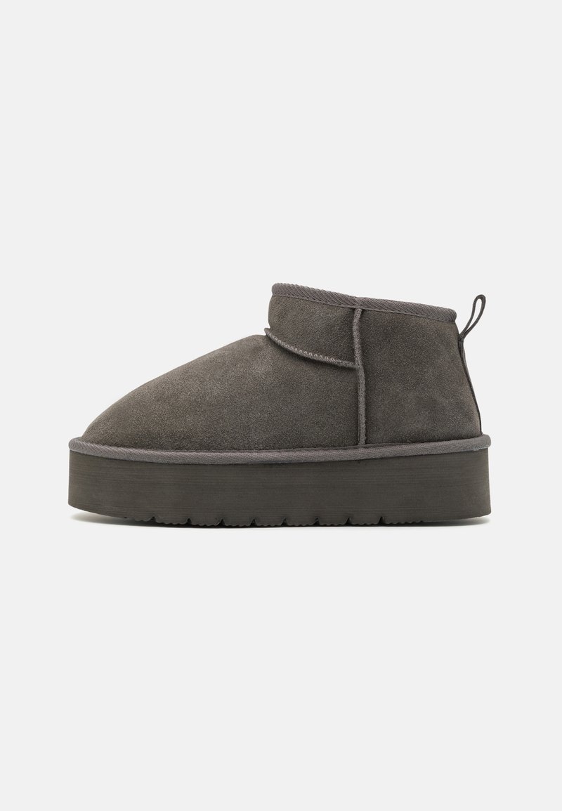 Grey suede ankle boot with a rounded toe, low shaft, textured surface, and a thick platform sole. Features a rear pull tab for easy wear.