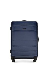 Valigia rigida blu navy con superficie texturizzata, scanalature orizzontali, doppie ruote, maniglia robusta e etichetta del marchio nera.