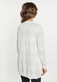 Cardigan ușor, cu mâneci lungi, de culoare albă, cu dungi texturate gri. Prezintă o croială lejeră și manșete și tiv ribbate.