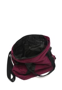 Otvorena maroonska i crna najlonska torba s patentnim zatvaračem i unutrašnjim džepom, odložena na bijeloj površini s vidljivim naramenicama i ručnim trakama.