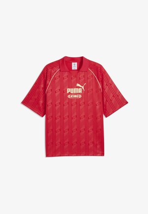 Czerwona sportowa koszulka Puma King z krótkim rękawem i kołnierzykiem, z wzorzystymi pionowymi paskami i kremowym logo Puma z przodu.