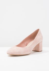 Světle růžové semišové lodičky s špičatou špičkou a středně vysokým blokovým podpatkem, s hladkým povrchem a minimalistickým designem.