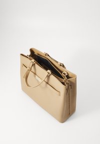 Beige lærveske med doble håndtak, glidelås og hardware i gullfarge. Innvendig har den en mørk tekstilfôr og lommer.