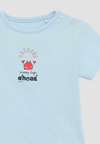 Helles blaues Babyshirt mit einem roten Krebs, der herzförmige Motive hält, und dem Text "Sonnige Tage voraus" unter einem Sonnen-Graphic sowie zwei Schulterdruckknöpfen.