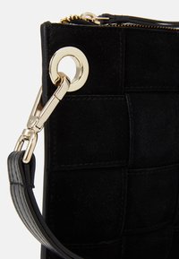 Černá semišová kabelka s prošívaným vzorem. Obsahuje zlatý kovový kroužek a odnímatelný kožený popruh. Zapínání na zip.