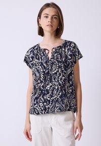 Blusa blu navy con motivo floreale bianco, maniche corte, scollatura a chiave e vestibilità morbida. Realizzata in tessuto leggero, adatta per un abbigliamento casual.