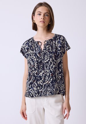 Blusa azul marino con patrón floral blanco, de mangas cortas, cuello en forma de llave y ajuste relajado. Fabricada con un tejido ligero, suitable para uso casual.