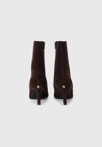 Brown suede ankle boots with a tapered heel, featuring a zip closure at the back and a small gold accent on the heel.