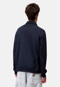 Sudadera de cuello redondo en azul marino con cuello, puños y dobladillo acanalados. Hecha de una tela suave, presenta un diseño simple y limpio sin logotipos visibles.