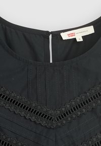 Abito nero con rifiniture in pizzo, pieghe verticali e cerniera sul retro. Realizzato in tessuto liscio, presenta un colletto rotondo e l'etichetta della taglia.