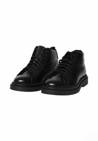 Stivali ankle in pelle nera con finitura liscia, punta rotonda e design a occhielli per i lacci. Suole in gomma flat. Costruzione minimalista.