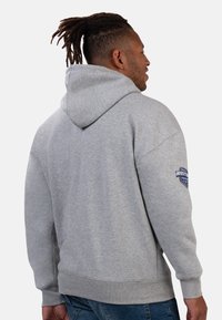 Gray hooded sweatshirt with ribbed cuffs and hem, featuring a logo patch on the left sleeve. Soft texture, relaxed fit, and drawstring hood.