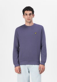 Felpa viola in cotone con scollatura rotonda e polsini a costine. Un piccolo logo a forma di farfalla gialla è posizionato sul lato sinistro del petto.
