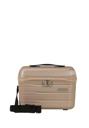 Compatta custodia cosmetica rigida beige con manico superiore, cerniera frontale con chiusure a scatto bloccate e tracolla nera staccabile.