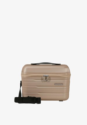 Compatta custodia cosmetica rigida beige con manico superiore, cerniera frontale con chiusure a scatto bloccate e tracolla nera staccabile.