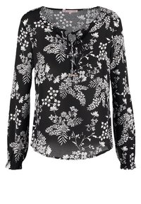 Blouse noire avec des motifs floraux blancs, manches longues avec des poignets élastiques, décolleté en v avec un nœud, et en tissu léger et lisse.