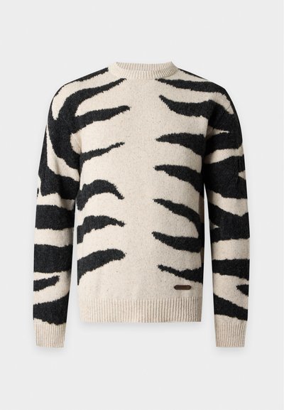 Pull en maille beige avec des rayures noires abstraites rappelant celles du zèbre, col rond, poignets et ourlet côtelés, présenté sur un fond uni.