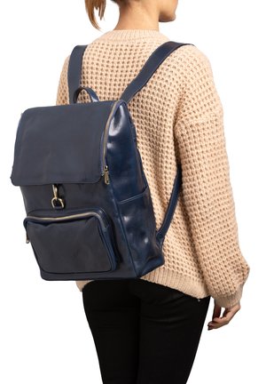 Sac à dos en cuir bleu marine avec fermeture à rabat, poche zippée à l'avant et bretelles ajustables. Texture lisse, forme rectangulaire.