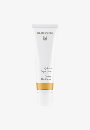 Tube en plastique blanc avec une bande dorée, portant l'étiquette "Crème de jour Quince" et "Quitten Tagescreme." Doté d'un logo de marque gris près du haut.