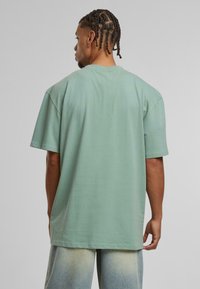 Zöld, oversized T-shirt, puha pamutból készült, rövid ujjú és kerek nyakú. Sima textúrájú, laza szabású.