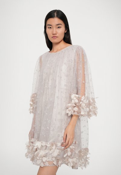 Robe légère et transparente de couleur rose pâle avec des manches 3/4, ornée d'appliqués floraux au niveau des poignets et de l'ourlet, embellie de petits sequins argentés partout.
