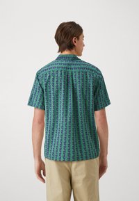 Cămașă cu mânecă scurtă, cu un model geometric în verde și bleumarin, design cu guler, cu tiv drept și din bumbac moale.