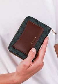 Zeleno-hnědý károvaný zipový peněženka se hladkým koženým detailem, zlatým logem a kontrastním prošíváním. Kompaktní design pro snadné ovládání.