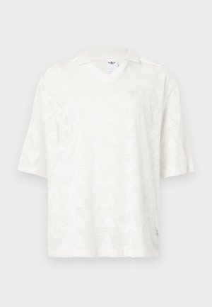 Polo blanc à manches courtes avec un motif triangulaire subtil, col en V, et petit logo Adidas sur la poitrine ainsi qu'une étiquette à l'intérieur du col.