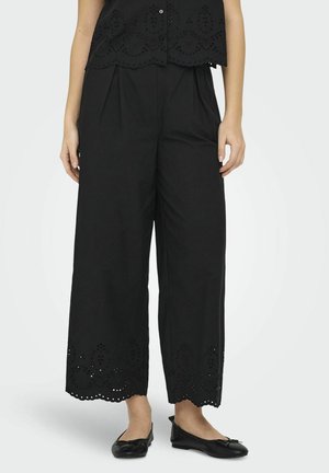 Pantalon noir à jambes larges avec un détail de ourlet perforé, fabriqué en tissu léger, présentant une coupe décontractée et des plis pour un confort supplémentaire.