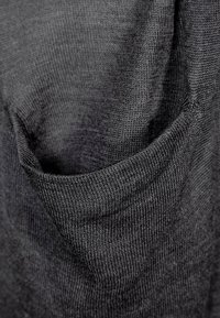 Mörkgrå stickad topp med rundad hals och en framficka med texturerad yta, som visar på en slät tygkvalitet.