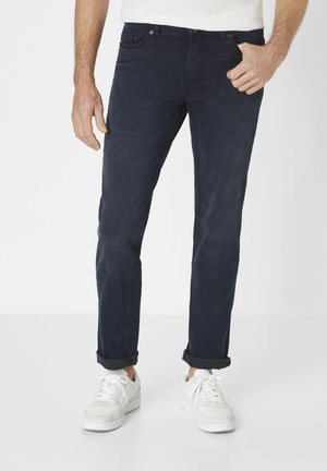 Dark blue denim jeans with a straight fit, rolled cuffs, five pockets, and subtle stitching details, paired with white sneakers.