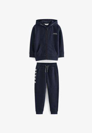 Hedvábně modrá bavlněná mikina s kapucí a předními kapsami, se zipovým uzávěrem, spojená s odpovídajícími teplákovými kalhotami s potiskem loga a elastickým pasem.