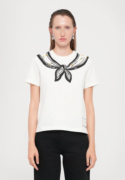 T-shirt en coton blanc avec un col marin noir, comportant des accents floraux et une étiquette au coin inférieur droit. Manches courtes et coupe décontractée.