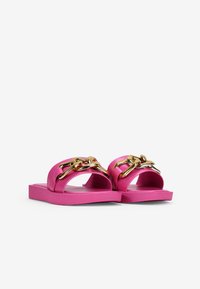 Pink slide sandals made of smooth rubber, featuring a gold chain accent across the top and a flat, rectangular sole.
