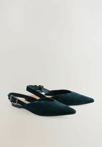 Tummanvihreät mokkanahkaiset slingback-kengät, joissa on terävä kärkiosuus ja säädettävä nilkkahihna. Tasapohja, jossa on vain vähän metalliosia ja ei koristeita.