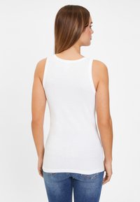 White sleeveless tank top with a round neckline, made of soft cotton, fitted design, smooth texture, and slightly curved hem at the back.