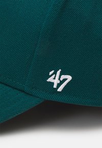 Donkergroene pet van gestructureerde stof, met een gestikt wit '47' logo aan de voorkant aan de linkerkant. De klep is gebogen.
