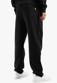 Črne trenirke iz mehke tkanine, z zadnjim žepom in emblemom Union Jack. Oblikovane z udobnim krojem in elastičnim pasom.