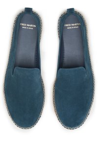 Chaussures en daim à enfiler de couleur teal, avec un bout arrondi et des surpiqûres contrastantes le long de la semelle. Détail intérieur : "FRED MARTIN FABRIQUÉ EN ESPAGNE."
