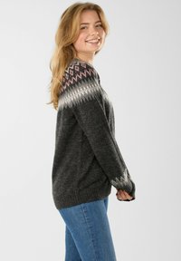Dark gray sweater with a Fair Isle pattern featuring pink, white, and gray at the shoulders. Long sleeves and ribbed hem for structure.